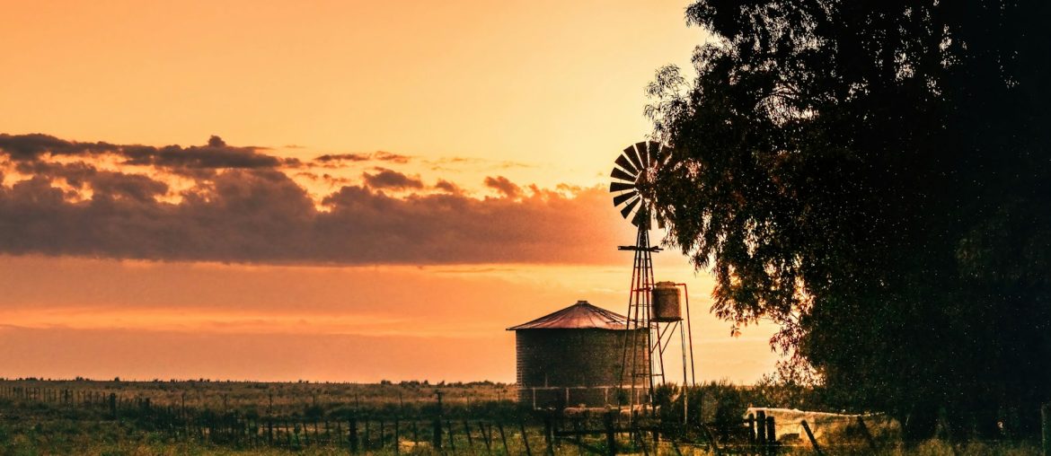 white and brown wooden house near green grass field during sunset